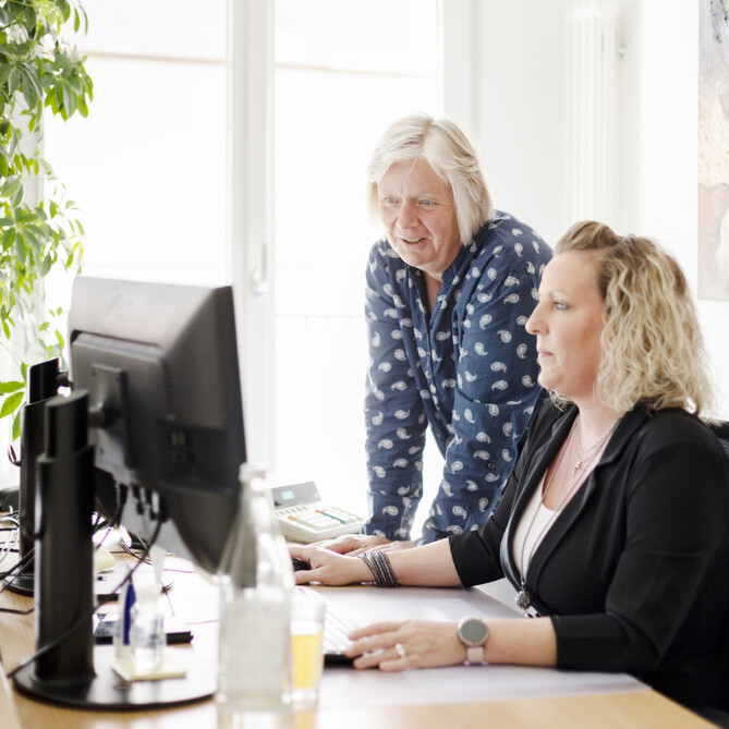 Zwei Frauen unterhalten sich vor einem Computer
