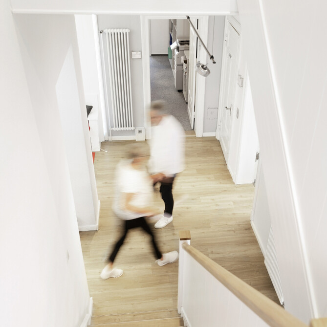 Zwei Personen gehen durch eine hellen Flur