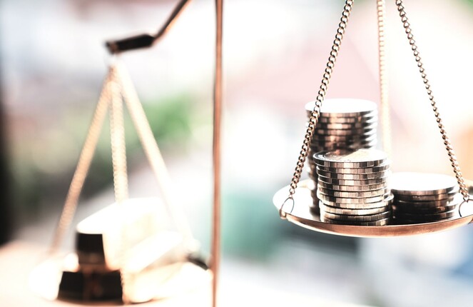 Rechteckiges Bild einer Waage mit Münzen drauf