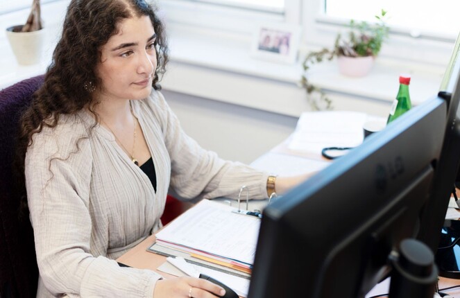 Rechtekiges Bild von einer ttplerin die am Computer arbeitet