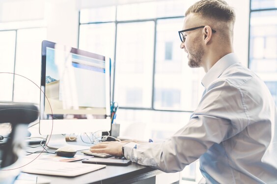 Ein ttp Mitarbeiter sitzt mit einem Hemd am Schreibtisch