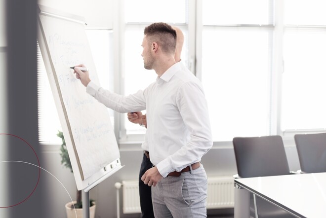 Mann steht an Flipchart und schreibt