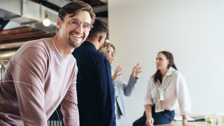 Lächelnder Mann mit Brille und weitere Personen