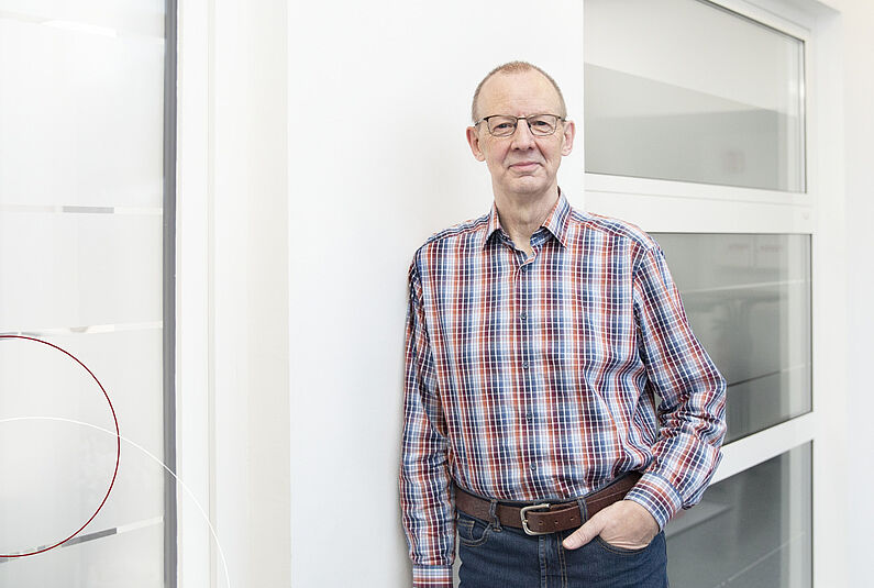 ttp Mitarbeiter lehnt an einer Bürowand.