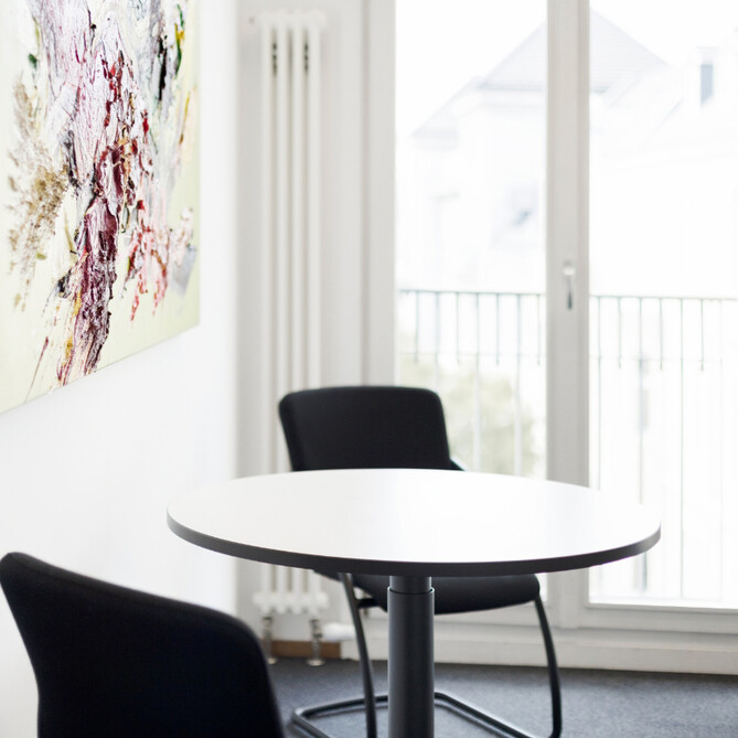 Ein weißer runder Tisch mit zwei schwarzen Stühlen