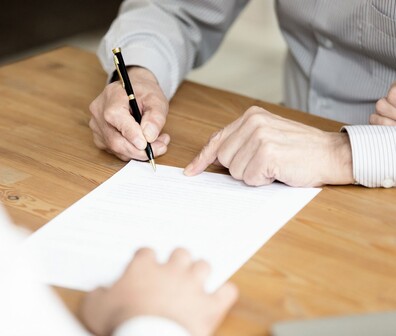 Quadratisches Bild von einer Person die ein Papier unterschreibt