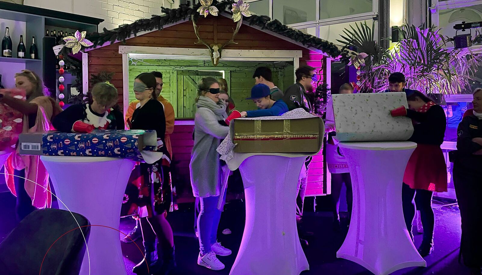 ttp-Mitarbeiter packen mit Bechern über den Händen Geschenke aus.