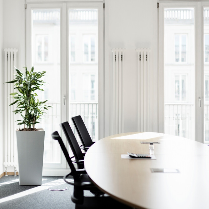 Ein heller Raum mit einem runden Tisch und schwarzen Stühlen