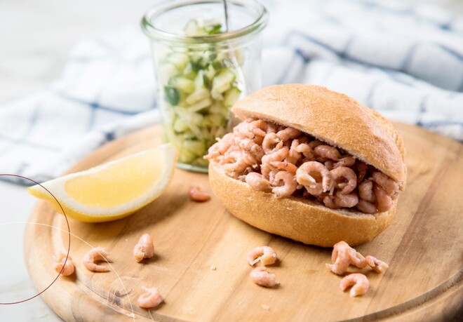 Ein Krabbenbrötchen auf einem Tisch mit einem Zitronenschnitz daneben
