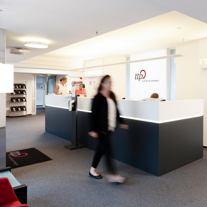 Eine Frau im Anzug geht durch ein ttp Büro