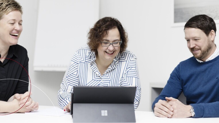 Kollegen sitzen um ein Tablet