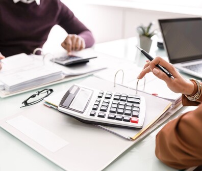 Quadratisches Bild von zwei Personen die auf einem Taschenrechner tippen