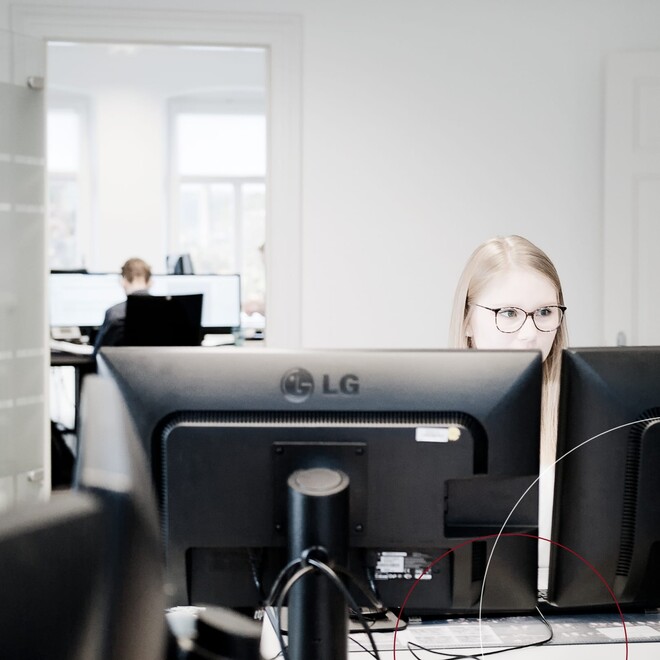 Blick in die Büros von ttp, im Vordergrund eine Mitarbeiterin am Computer