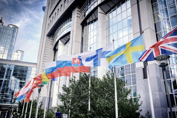 Flaggen unterschiedlicher Länder vor einer Hochhauskulisse.