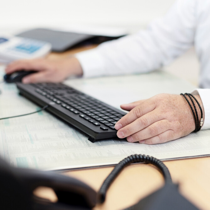 Eine schwarze Computertastatur steht auf einem ttp Schreibtisch