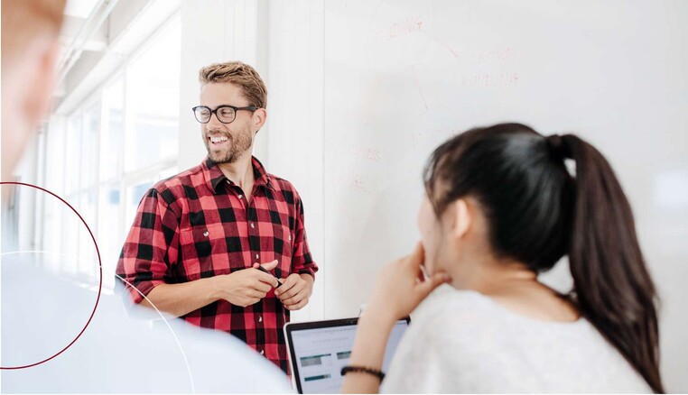 Ein Mann im karierten Hemd steht vor einer Tafel