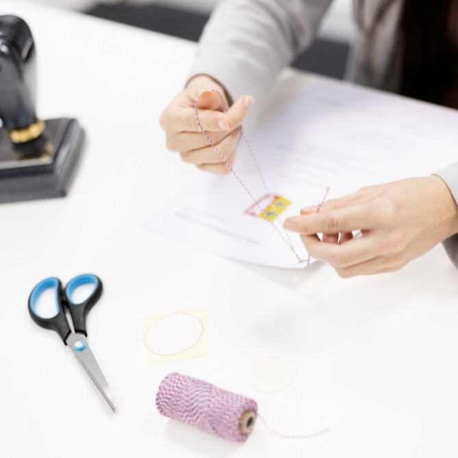 Eine ttplerin sitzt mit Schere und Stift am Tisch
