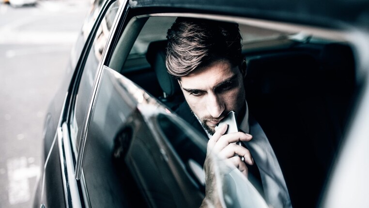 Mann mit Smartphone in einem Auto