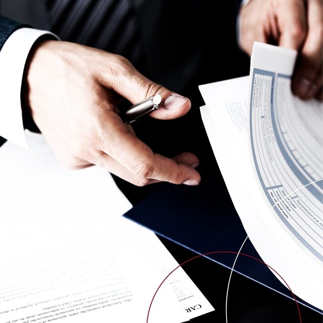 Hände mit Stift, die durch eine Akte blättern