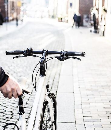 Ein Mann schiebt ein weißes Fahrrad