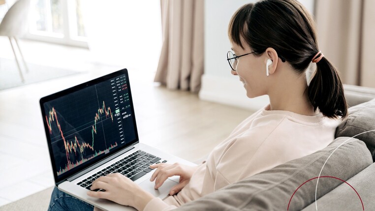 Eine Frau sitzt mit einem Laptop auf dem Sofa.