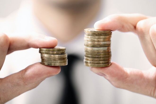 Ein Mann hält zwei Stapel an Münzen in seinen Händen