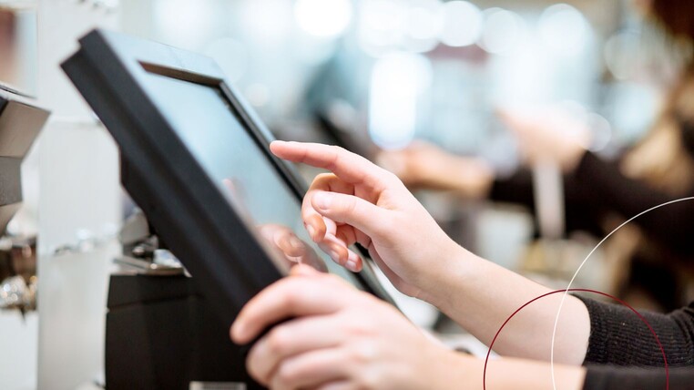 Hände, die etwas in einen Kassenmonitor tippen.