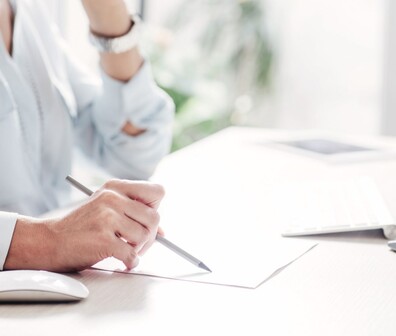Quadratisches Bild von einer Frau die auf einem Papier schreibt