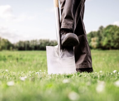 Quadratisches Bild von einem Mann der einen Spatenstich setzt