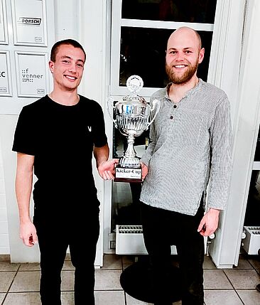 Zwei Männer halten einen Pokal