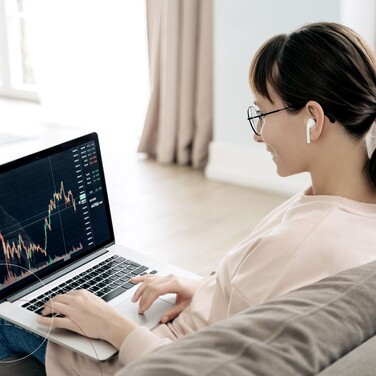 Eine Frau sitzt mit einem Laptop auf dem Sofa.