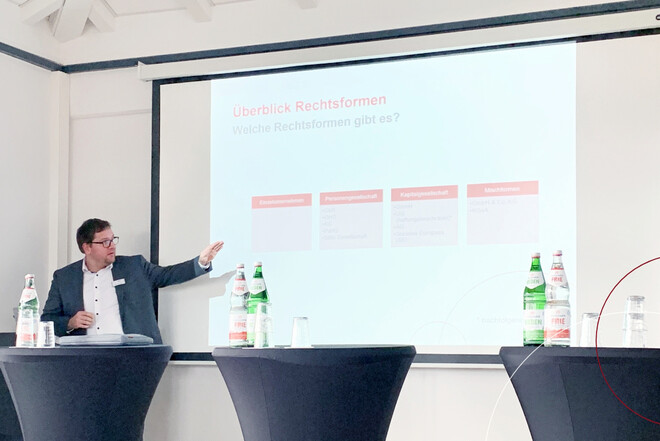 Mann steht an Präsentation und zeigt auf etwas