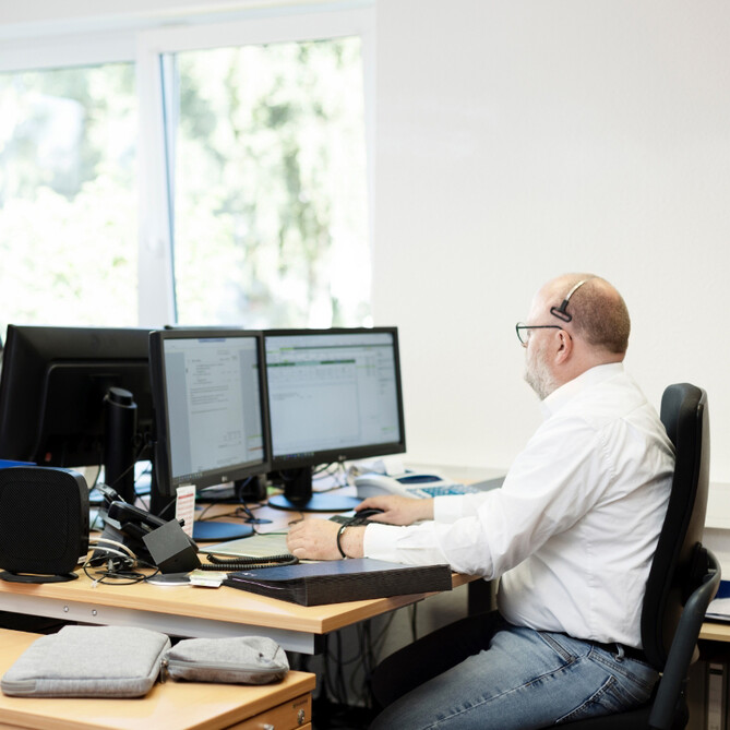 Ein ttp Mitarbeiter sitzt mit Headset am Schreibtisch