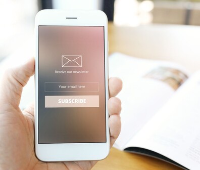 Quadratisches Bild von einer Person die ein Smartphone in der Hand hält