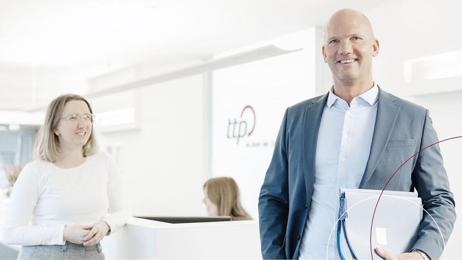 Zu sehen sind zwei ttp-Mitarbeiter vor dem Empfangstresen.