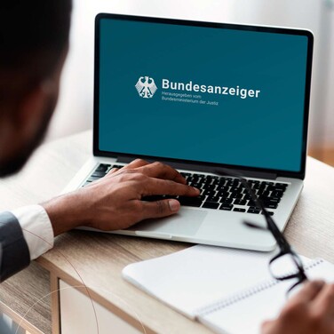 Ein Mann im Anzug arbeitet an einem silbernen Laptop