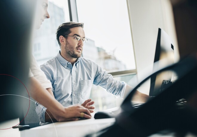 Zwei Kollegen beraten sich am Arbeitsplatz.