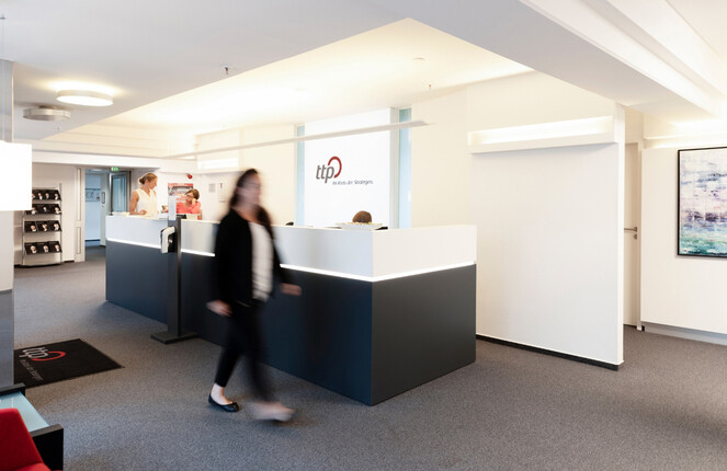 Eine Frau im Blazer geht durch einen ttp Flur