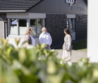 Quadratisches Bild von drei ttpler die vor einem ttp Büro stehen