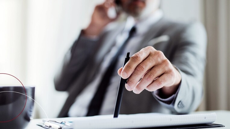 Telefonierender Mann halt einen Stift in der Hand
