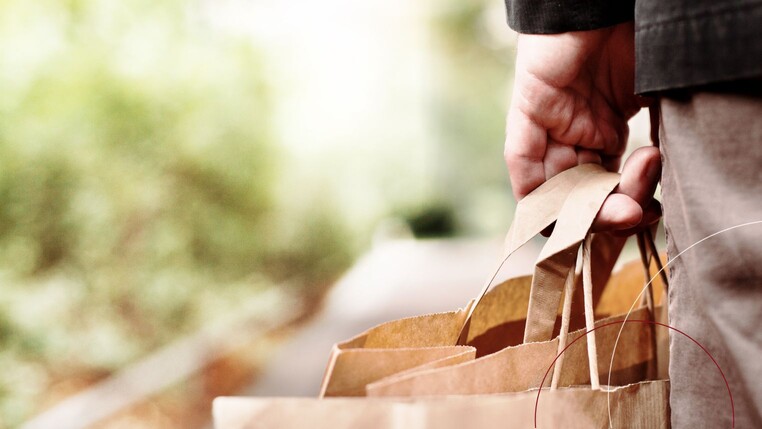 Ein Mann trägt mehrere Einakufstüten