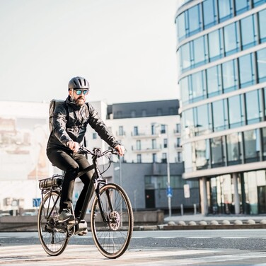 Fahrradfahrer fährt an einer Glasfassade vorbei