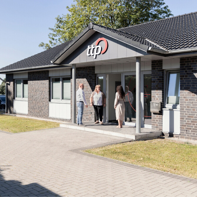 Drei ttp Mitarbeiter stehen vor dem Gebäude