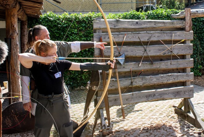 Eine Mitarbeiterin von ttp versucht sich im Bogenschießen.