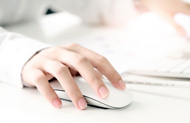 Rechteckiges Bild von einer Person die eine Computermaus in der Hand hält